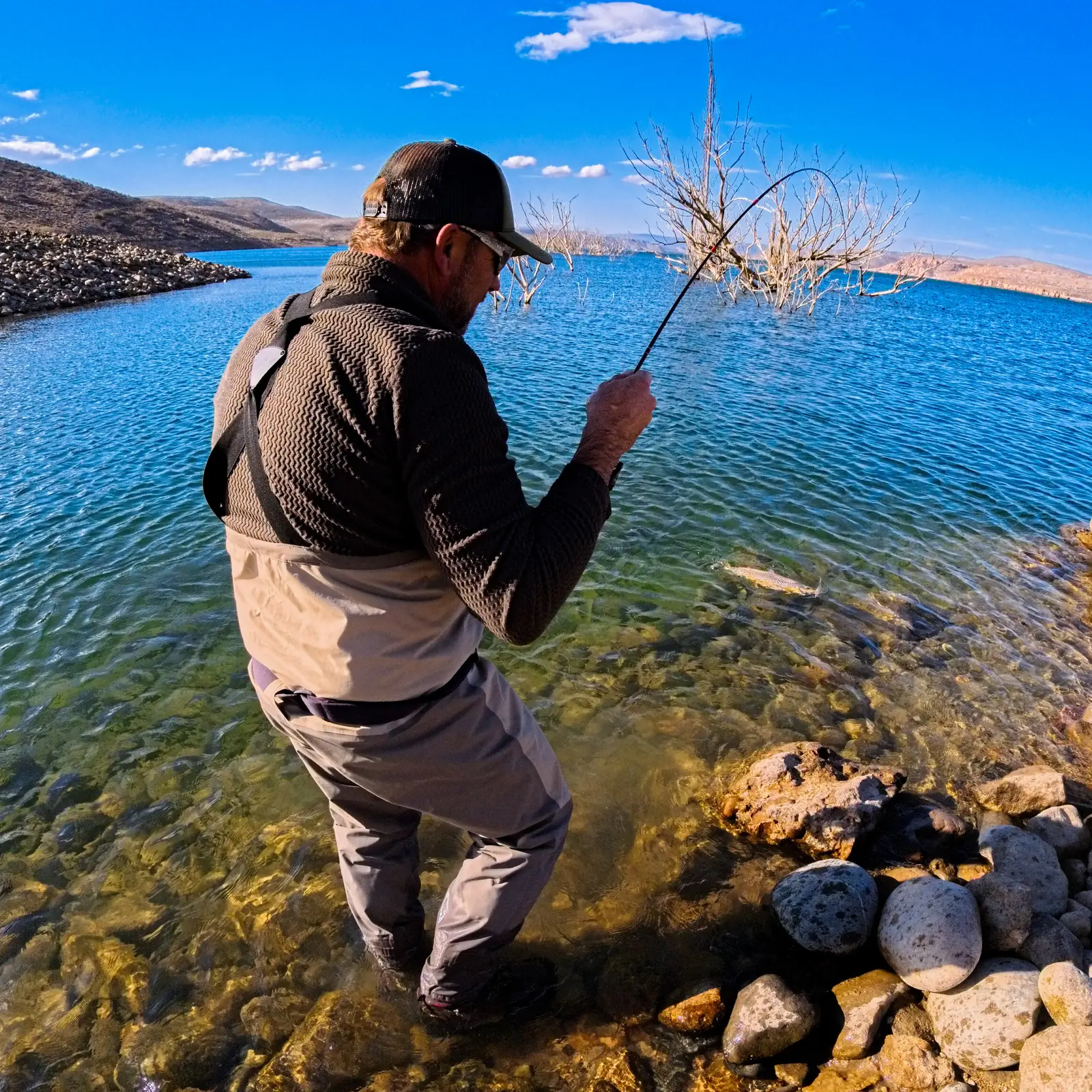 Pescador con mosca junto al embalse