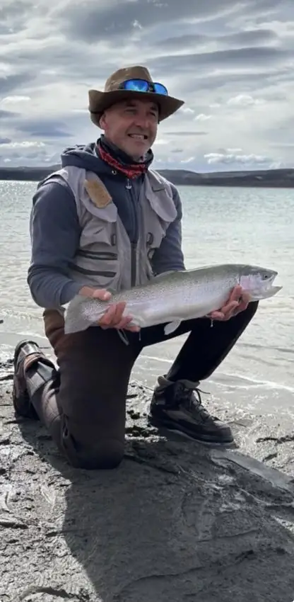 Pescador con trucha arcoíris junto al lago