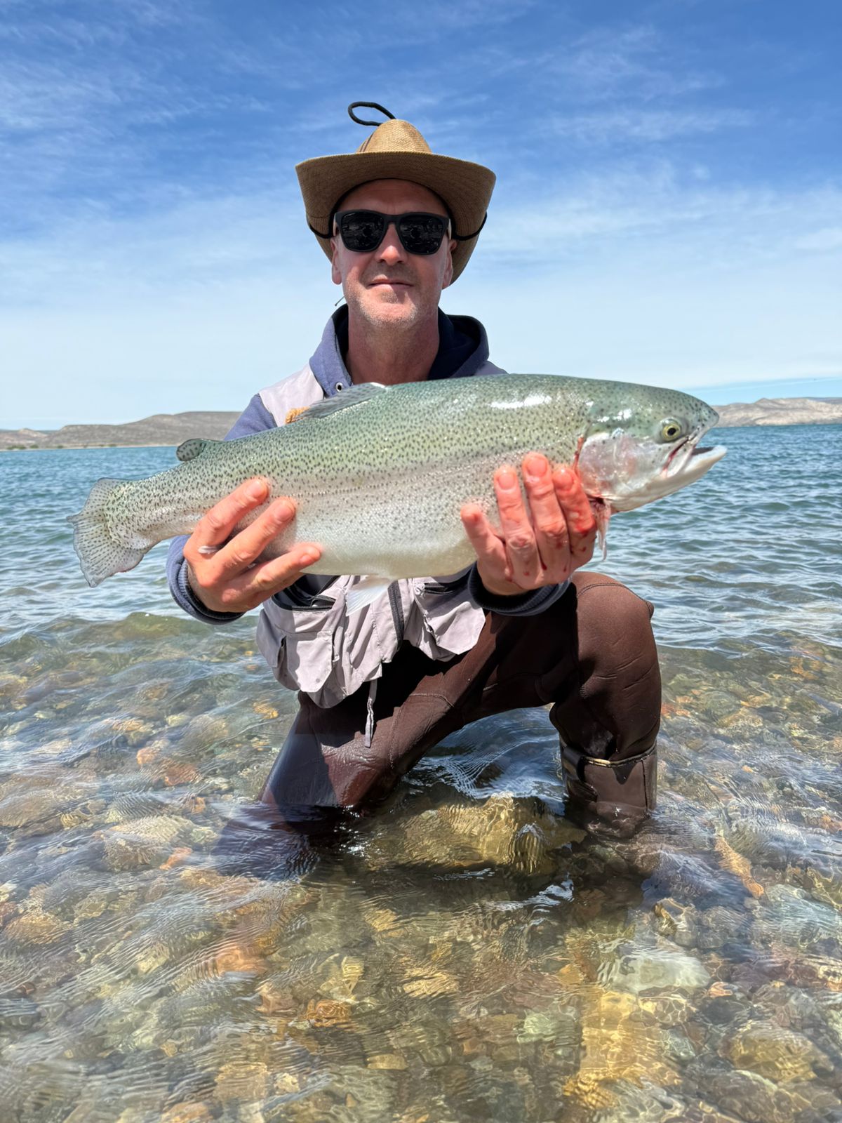 Pescador con trucha arcoíris en el Embalse Piedra del Águila